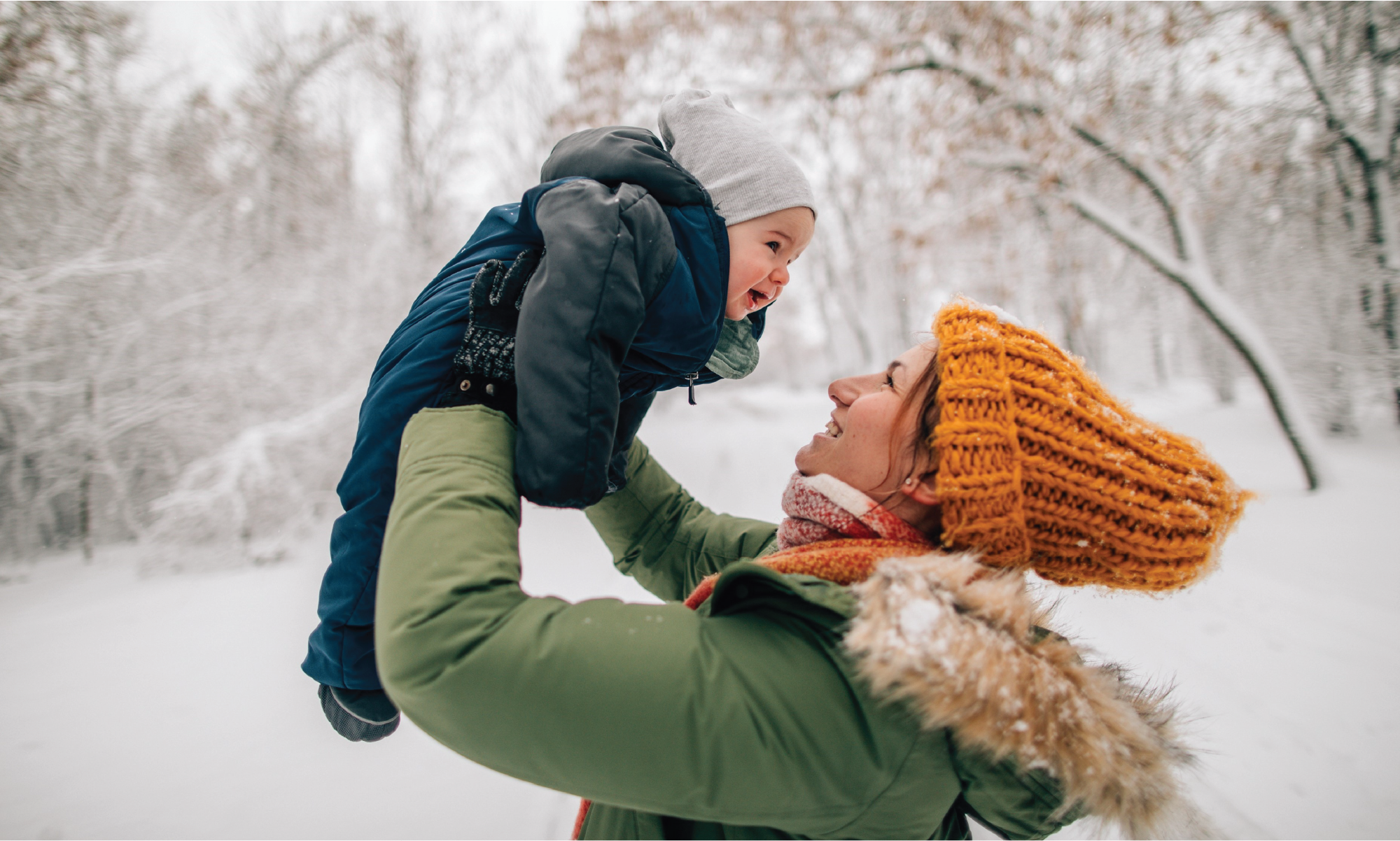 Mamma lyfter upp baby i luften och båda ler