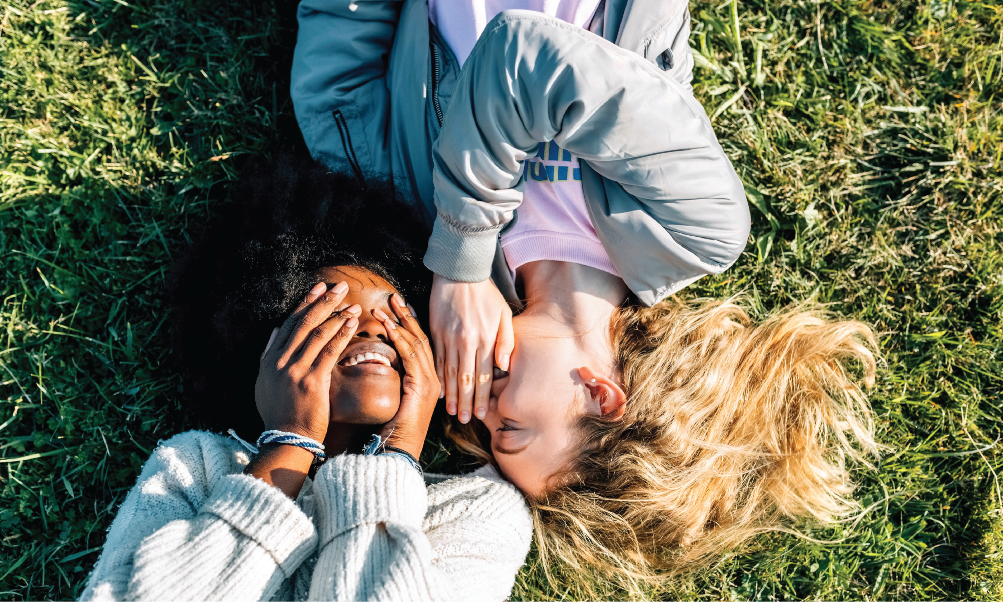 Ung fnissig kvinna viskar i en annan kvinnas öra. 