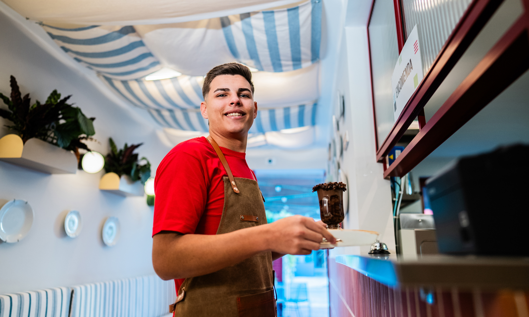 Ung glad kille på jobbet som servitör. håller i en kaffekopp.