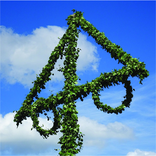 Grönklädd Midsommarstång mot blå himmel